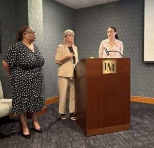 3 females around a lectern